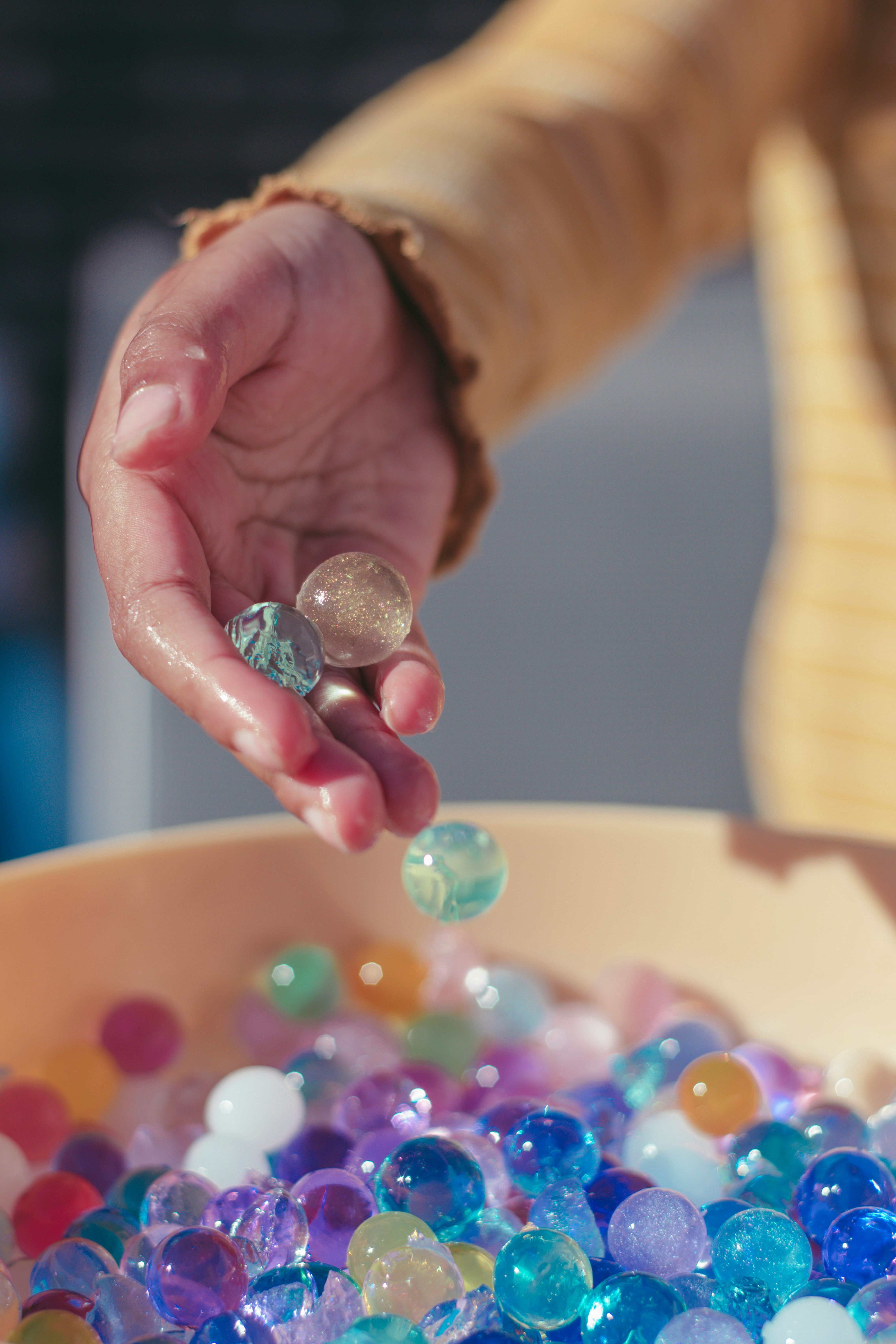 Image of someone's hand allowing marbles to drop into a container