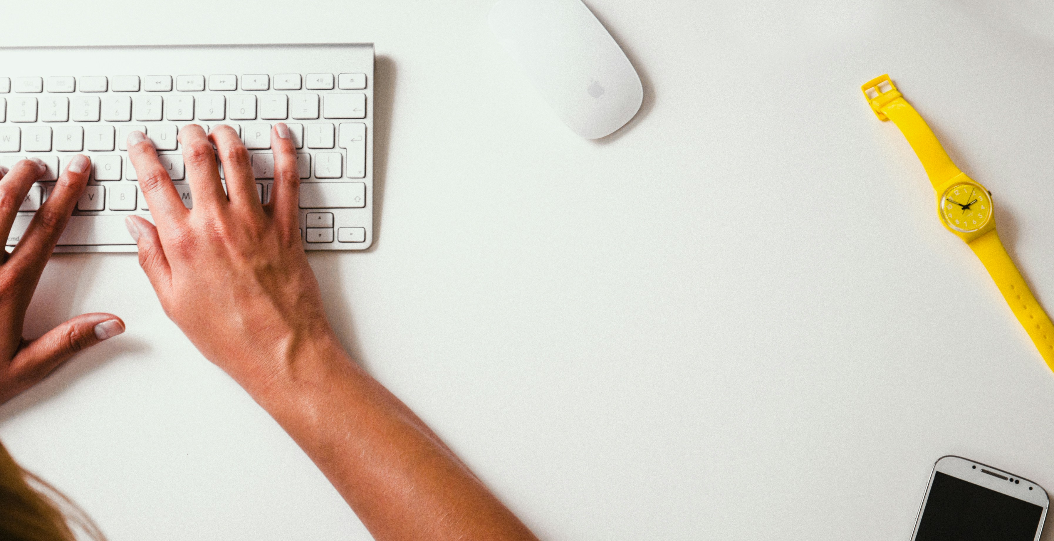 Header image for the contact page - hands typing on a keyboard with a view from above the desk